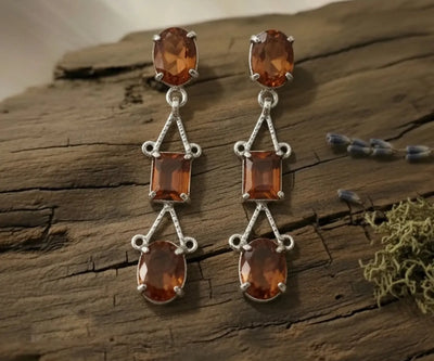 Root drop earrings highlighting Garnet in orange and green.